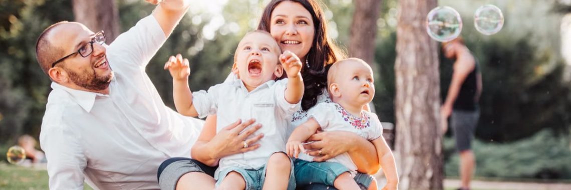 Joyful family enjoying a sunny day in the park while playing with bubbles.